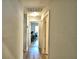 Hallway with light walls and wood floors leads to a room with a desk and rolling office chair at 879 Orleans Dr, Eagle Lake, FL 33839
