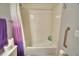 Tiled bathtub and shower with grab bar and shower curtain, featuring a full wall of neutral-toned tiles at 879 Orleans Dr, Eagle Lake, FL 33839