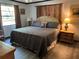 Comfortable bedroom with wood floors, decorative curtains, side tables and lamps on each side of the bed at 9402 Cat Track Trl, Lake Wales, FL 33898