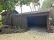 Rustic wooden carport and shed sit on a stone paver driveway with mature foliage at 9402 Cat Track Trl, Lake Wales, FL 33898