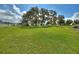Large green backyard with mossy trees framing a view of the bright white home in the distance on a partly cloudy day at 1042 Golden Bough Rd, Lake Wales, FL 33898