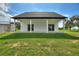 A view of the modern home's rear facade and covered patio that leads to a sprawling green lawn at 1042 Golden Bough Rd, Lake Wales, FL 33898