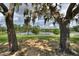 Lush backyard framed by majestic trees, offering a tranquil view of the shimmering lake, perfect for relaxation at 1042 Golden Bough Rd, Lake Wales, FL 33898
