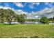 An expansive green backyard gently slopes toward a serene lake reflecting the cloudy sky, with trees enhancing the view at 1042 Golden Bough Rd, Lake Wales, FL 33898