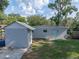 The backyard has a detached garage with a blue door, storage shed, and mature trees at 1140 W Seminole Trl, Bartow, FL 33830