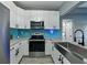 Updated kitchen featuring stainless appliances, white cabinetry, blue backsplash, and breakfast bar seating at 1140 W Seminole Trl, Bartow, FL 33830