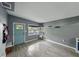 Bright living room featuring modern gray walls, light wood-look tile floors, and a striking blue front door at 1140 W Seminole Trl, Bartow, FL 33830