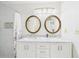 Bathroom with a double sink vanity with marble countertops, gold-trimmed mirrors, and a tiled shower at 14191 Se 25Th Ave, Summerfield, FL 34491