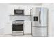 Stainless steel appliances, white cabinetry, and decorative backsplash in this modern kitchen at 14191 Se 25Th Ave, Summerfield, FL 34491