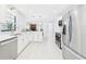 Modern kitchen with stainless steel appliances, white cabinets, and decorative tile backsplash overlooking the living area at 14191 Se 25Th Ave, Summerfield, FL 34491