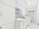 Bright laundry room with modern cabinets, patterned wall, sink, and washer/dryer units at 14191 Se 25Th Ave, Summerfield, FL 34491