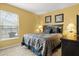 Bedroom with a queen bed and yellow walls, complimented by decorative artwork and window views at 151 Hideaway Beach Ln, Kissimmee, FL 34746