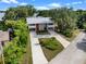 Aerial shot of a modern home with a red door, long driveways and is surrounded by lush trees near a serene lake at 1540 N Lake Mirror Nw Dr, Winter Haven, FL 33881