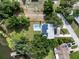 Aerial view of property featuring lake access with a ramp, a pool, solar panels, and lush greenery for privacy at 1540 N Lake Mirror Nw Dr, Winter Haven, FL 33881