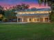 Modern home with a backyard pool, a lush lawn, and amazing sunset colors in the sky at 1540 N Lake Mirror Nw Dr, Winter Haven, FL 33881