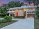 Modern home with white metal roof, red door, tall windows, lush landscaping, and a winding driveway at 1540 N Lake Mirror Nw Dr, Winter Haven, FL 33881