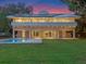 Beautiful modern home with a backyard pool, a lush lawn, and amazing sunset colors in the sky at 1540 N Lake Mirror Nw Dr, Winter Haven, FL 33881