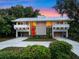 Beautiful modern home with white metal roof, red door, tall windows, lush landscaping and long driveway at 1540 N Lake Mirror Nw Dr, Winter Haven, FL 33881