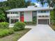 Stunning contemporary home featuring a white metal roof, tall windows, red door, and covered parking at 1540 N Lake Mirror Nw Dr, Winter Haven, FL 33881