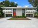 Contemporary home displaying symmetrical architecture, a vibrant red door, generous parking, and meticulous landscaping at 1540 N Lake Mirror Nw Dr, Winter Haven, FL 33881