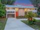 Stylish home boasting a metal roof, bright red front door, and a long driveway leading to a spacious carport at 1540 N Lake Mirror Nw Dr, Winter Haven, FL 33881
