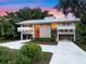 Beautiful modern home with white metal roof, red door, tall windows, lush landscaping and long driveway at 1540 N Lake Mirror Nw Dr, Winter Haven, FL 33881