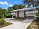 Modern home featuring a striking exterior design, clean lines, expansive driveway, and lush surrounding greenery at 1540 N Lake Mirror Nw Dr, Winter Haven, FL 33881