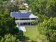 Aerial view showcases a home with solar panels, a pool, a well-manicured lawn, and surrounding trees for privacy at 1540 N Lake Mirror Nw Dr, Winter Haven, FL 33881