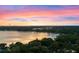 Scenic aerial view of a lake at sunset showcasing the horizon with trees in the foreground and city buildings in the distance at 1540 N Lake Mirror Nw Dr, Winter Haven, FL 33881