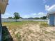 A large fenced in back yard with sparse grass and blue skies offers room to roam and play at 2018 Misty Morning Dr, Winter Haven, FL 33880