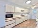 Functional kitchen featuring white cabinets, stainless sink, laundry and microwave at 254 Winter Ridge Blvd # 254, Winter Haven, FL 33881