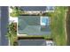 Overhead view of a home with a green roof and a screened-in pool in a neighborhood next to a lake at 263 Reserve Dr, Davenport, FL 33896