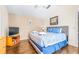 Comfortable bedroom featuring wood floors, neutral walls, artwork, a TV, and a queen-size bed with blue comforter at 263 Reserve Dr, Davenport, FL 33896