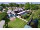 Aerial view showcases a property with solar panels, screened pool, lush greenery, and waterfront access at 3705 Pine Cir, Lake Wales, FL 33898