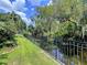 Backyard view showcases a well-maintained lawn and a tranquil waterway beyond a classic wrought iron fence at 3705 Pine Cir, Lake Wales, FL 33898