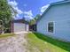 Side yard view showcasing a detached garage/workshop, blue siding, and a well-maintained lawn under a bright sky at 3705 Pine Cir, Lake Wales, FL 33898