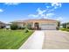 Inviting home with a spacious driveway leading to a two-car garage, complemented by lush lawn and mature landscaping at 413 Ruby Lake Pl, Winter Haven, FL 33884