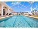 Large in ground swimming pool is fully screened, surrounded by potted plants and a waterfall feature at 413 Ruby Lake Pl, Winter Haven, FL 33884
