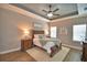 This is a primary bedroom featuring wood floors, tray ceiling, and natural lighting at 421 Riders Loop, Auburndale, FL 33823