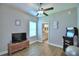 This is a secondary bedroom with wood floors, a ceiling fan, and a view of the bathroom at 421 Riders Loop, Auburndale, FL 33823