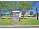 Community access point featuring a security keypad and camera, set amidst manicured landscaping and mature trees at 421 Riders Loop, Auburndale, FL 33823