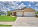 Beautiful single-story home with a two-car garage, lush green lawn, and lovely desert landscaping at 421 Riders Loop, Auburndale, FL 33823