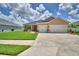 Inviting single-story home featuring a three-car garage, well-manicured lawn, and lush landscaping at 421 Riders Loop, Auburndale, FL 33823