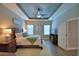 A serene main bedroom with a decorative tray ceiling, plush carpet and two windows for ample natural light at 421 Riders Loop, Auburndale, FL 33823