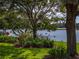 Picturesque view of the lake from the backyard, enhanced by mature trees and colorful landscaping at 4356 Ashton Club Dr, Lake Wales, FL 33859