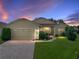 Charming one-story home featuring well-manicured lawn, brick driveway, and a cozy, inviting entrance at twilight at 4356 Ashton Club Dr, Lake Wales, FL 33859