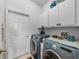 Laundry room with blue washer and dryer and white cabinets for storage at 4356 Ashton Club Dr, Lake Wales, FL 33859