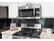 Close up view of kitchen featuring stainless steel appliances, gas stove, and black tile backsplash at 436 China Berry Cir, Davenport, FL 33837