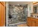 Beautiful shower with stone floor and blue brick-style walls, next to a wooden vanity with granite countertop at 4949 Lake Kotsa Dr, Lake Wales, FL 33898