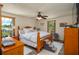 Well-lit bedroom featuring a large bed, wood furniture, a ceiling fan, and two windows at 4949 Lake Kotsa Dr, Lake Wales, FL 33898